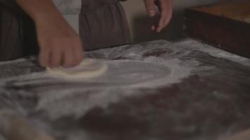 l'impasto del pane viene lanciato a mano e arrotolato con il mattarello e cosparso di farina preparata per la cottura video