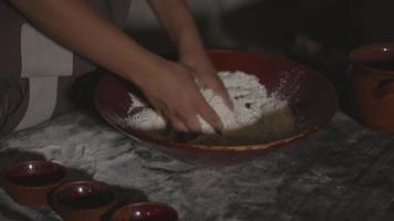 les mains mélangent la farine et l'eau dans un bol pour la pâte à pain