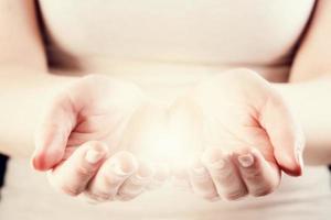 Light in woman hands. Giving, protect, care, energy concept. photo