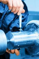 Worker measuring on industrial turning machine. Industry photo