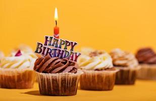 Birthday muffin with candle on yellow background. photo
