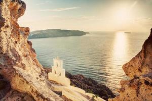 Cliff, volcanic rocks and a traditional chapel on Santorini island, Greece photo