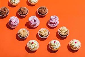 pastelitos de colores en tres filas sobre fondo naranja. foto