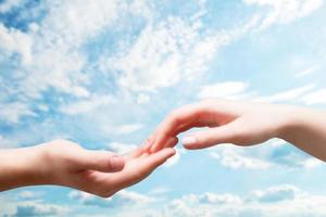 Man and woman hands touch in gentle, soft way on blue sunny sky photo