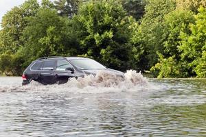 coche tratando de conducir contra inundaciones en la calle en gdansk, polonia. foto