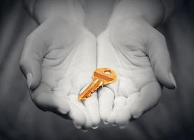 Gold key in hand in gesture of giving. Concept of success in live, business solution, real estate etc photo