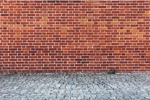 Retro red brick wall and cobblestone pavement. photo