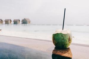 Coconut with a straw standing. Ocean view photo