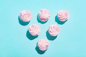 Triangle of pink muffins on blue background. photo