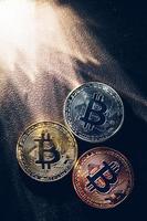 Three colorful bitcoin coins and beams of light. photo