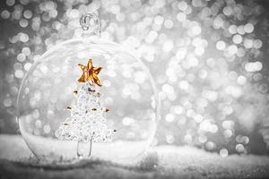 bola de cristal de navidad con árbol de cristal dentro de la nieve foto