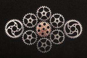 Rose-gold cogwheel surrounded by metal cogwheels photo