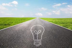 Light bulb symbol on long empty straight road. Environment, idea photo
