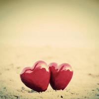 Two red hearts on the beach symbolizing love, Valentine's Day, romantic couple photo