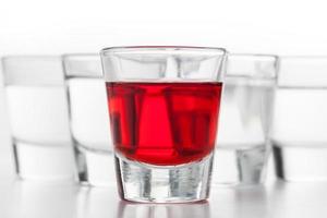 vasos de alcohol. uno rojo con sabor, los otros vodka limpio. foto
