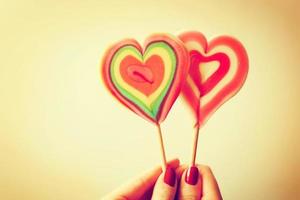 Colorful heart shaped lollipops in woman hand photo