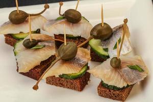 Herring fillet canape with caperberry photo