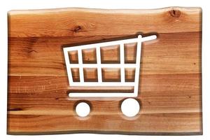 Shopping cart sign, symbol cut in wooden board isolated on white. photo