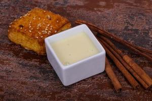 Condenced milk in the bowl with sinnamon and pastry photo