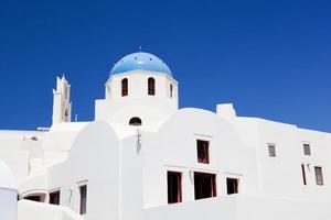White buildings and church with blue dome in Oia or Ia on Santorini island, Greece photo