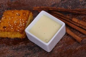 Condenced milk in the bowl with sinnamon and pastry photo