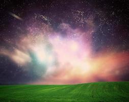 Field of grass under dream galaxy sky, space, glowing stars. photo