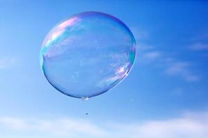 One clean soap bubble flying in the air, blue sky. photo