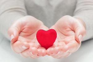 Small red heart in woman's hands in a gesture of giving, protecting photo