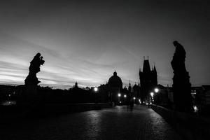 Prague, Czech Republic, 2022 - Charles Bridge at sunrise, Prague, Czech Republic. Statues, medieval towers in black and white photo