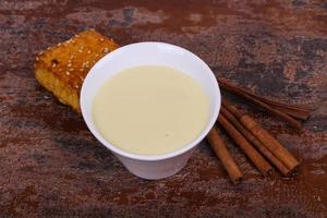 Condenced milk in the bowl with sinnamon and pastry photo