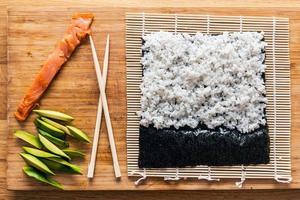 Preparing sushi. Salmon, avocado, rice and chopsticks on wooden table. photo