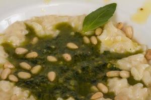 photo of delicious risotto dish with herbs and cedar nut on white background