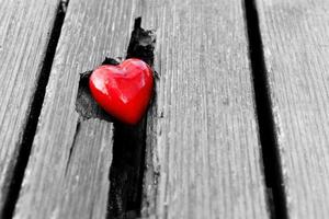 corazón rojo en la grieta del tablón de madera. símbolo de amor foto