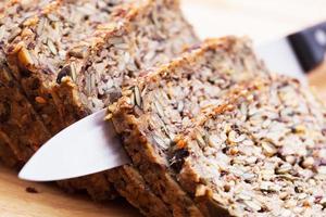cuchillo en pan integral, pan integral sobre mesa de madera. alimentos orgánicos y saludables foto