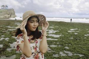 A young cute Asian girl wearing a sun hat is relaxing on the blue sky beach at Gunungkidul, Indonesia photo