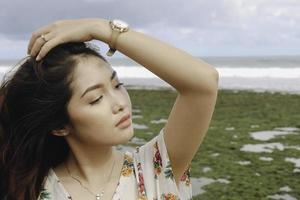 una joven y hermosa mujer asiática volteando su cabello en la playa foto