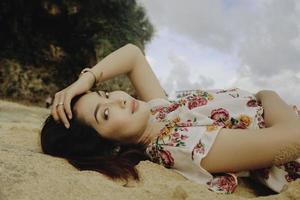 Close up top view of a smiling woman lying and relaxing on beach sand photo