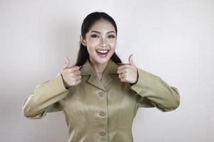 A young Asian woman in brown khaki uniform showing thumbs up or OK sign. Indonesian government worker. photo