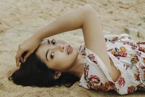 Close up top view of a smiling woman lying and relaxing on beach sand photo