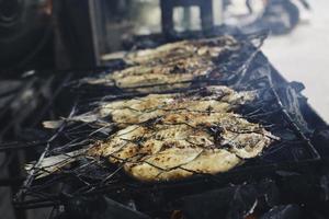 pescado a la parrilla con carbón a la venta en el mercado de comida callejera o en un restaurante en indonesia foto