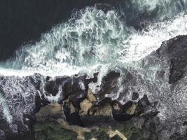 Top down aerial view of giant ocean waves crashing and foaming in coral beach photo