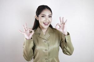 A young Asian woman in brown khaki uniform showing thumbs up or OK sign. Indonesian government worker. photo