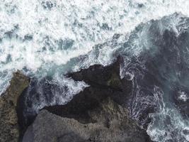 Top down aerial view of giant ocean waves crashing and foaming in coral beach photo