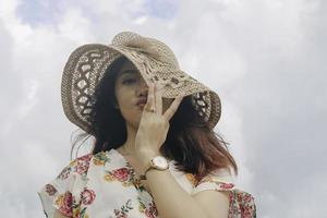 A young cute Asian girl wearing a sun hat is relaxing on the blue sky beach at Gunungkidul, Indonesia photo