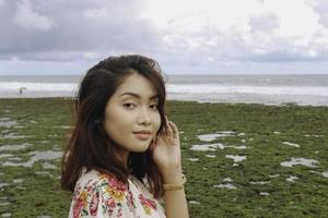 A young Asian girl on the beach is smiling at the camera at Gunungkidul, Indonesia photo