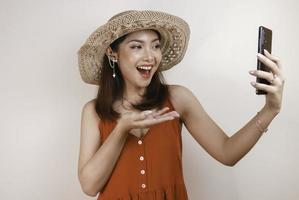 Excited and smiling young Asian woman pointing finger at smartphone in her hand photo