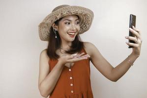 Excited and smiling young Asian woman pointing finger at smartphone in her hand photo