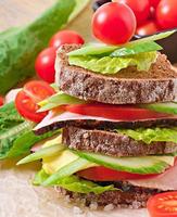 Sandwich with ham and fresh vegetables on a wooden background photo