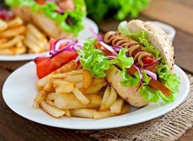 Hotdog with ketchup mustard and lettuce on wooden background. photo