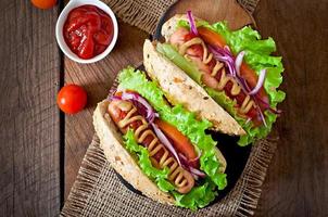 Hotdog with ketchup mustard and lettuce on wooden background. photo